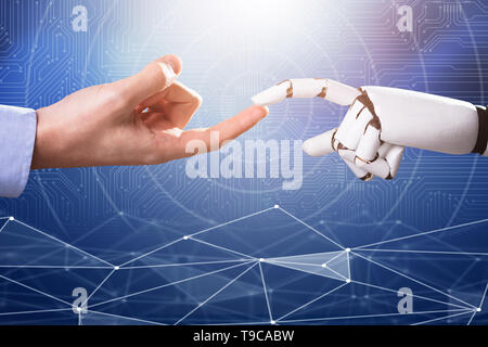Robot Touching Man's Index Finger Against Digital Backdrop Stock Photo