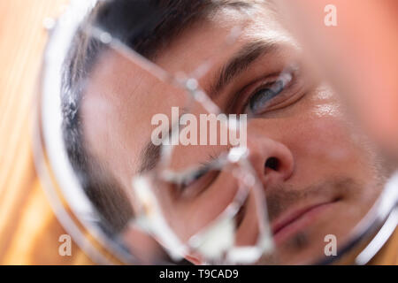 Close-up Of Young Man Looking At His Face In A Broken Mirror Stock Photo