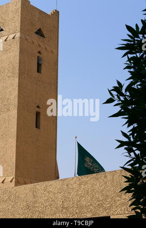 The flag of the Kingdom of Saudi Arabia next to a traditional arabic building Stock Photo