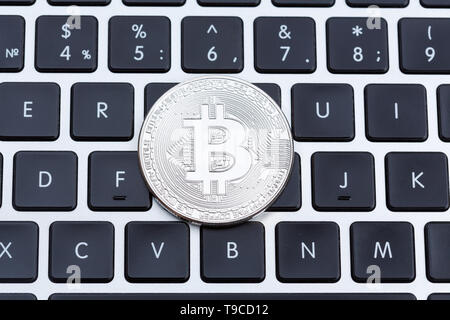 Silver bitcoin on computer key board close-up. Stock Photo
