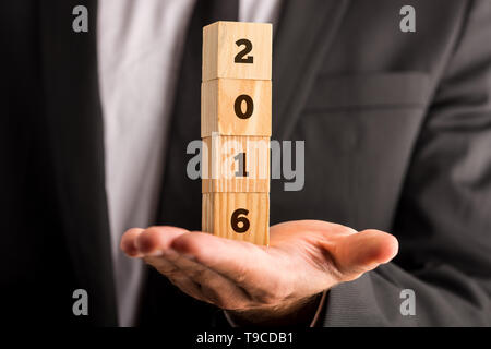 Male hand holding four stacked wooden cubes with 2016 sign. Stock Photo