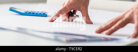 Wide view image of an engineer working on a project with calculator and ruler on his paper. Stock Photo