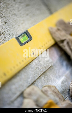 Workman using a builders spirit level to ensure that the wall tiles that he is installing are level and horizontal. Stock Photo
