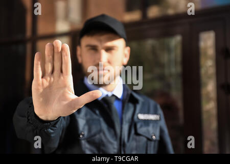 Male security guard showing Stop gesture outdoors Stock Photo