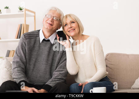 Talking With Relatives. Senior Couple Sharing Phone Stock Photo