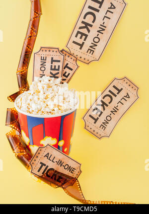 Movie tickets, film strips and popcorn on blue background. Copy space for text. Stock Photo