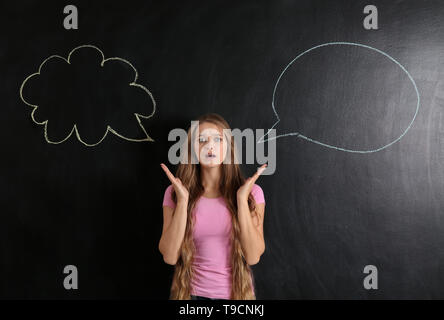 Confused young woman and blank speech bubbles on dark background Stock Photo