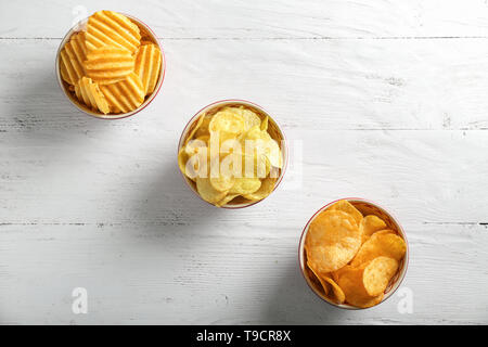 Bowls with tasty crispy potato chips on white wooden table Stock Photo