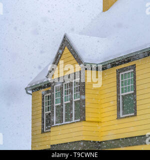 Square Snowy yellow home viewed through falling snow Stock Photo
