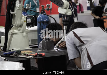 Bangkok, Thailand - May 10, 2019: Industrial technician operating robotic welding arm in Intermach 2019 Stock Photo