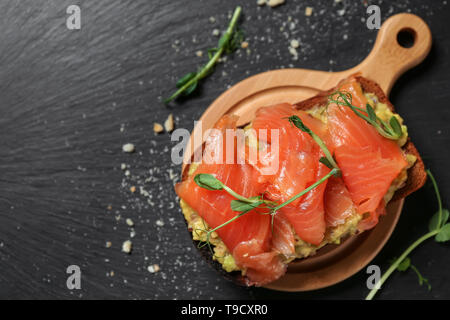 Tasty sandwich with salmon and avocado on dark table Stock Photo