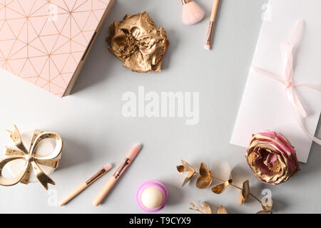 Composition with beautiful golden roses and makeup brushes on grey background Stock Photo