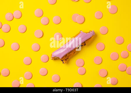 Bitten eclair with chocolate chips on color background Stock Photo
