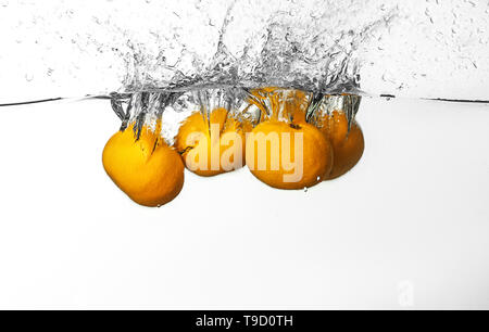 Falling of tangerines into water on white background Stock Photo