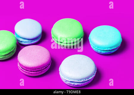 Closeup of homemade multi colored sweet macaroons on purple background on table. Colorful cakes Stock Photo