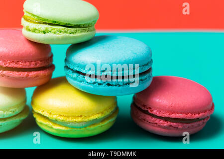 Colorful macarons cakes on a blue background, closeup pink, yellow green French dessert for Breakfast Stock Photo