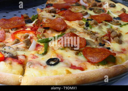 Close up view on a tasty Pizza with salami, beef, peppers, tomatoes, pepperoni and olives Stock Photo