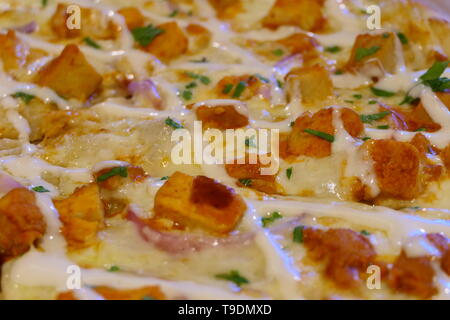 Close up view on a tasty chicken pizza with a lot of cheese and chicken with small onion pieces Stock Photo