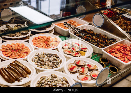 Seafood selection at the buffet counter. sea mussels in a disposable plate surrounded with fish and prawns on the counter. Stock Photo