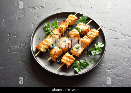 Grilled salmon kebab. Barbecue salmon skewers on black stone background. Stock Photo