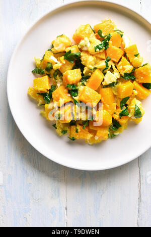 Pumpkin and egg stir fry in thai style. Stir-fried pumpkin with eggs on plate over white wooden background with copy space. Top view, flat lay Stock Photo