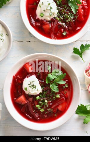 Tasty beetroot soup with greens and sauce in bowl on white wooden background. Top view, flat lay Stock Photo