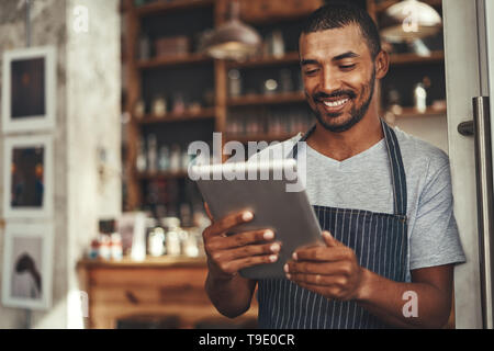 Successful barista cafe owner looking at digital tablet Stock Photo