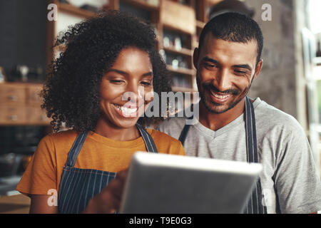 Smiling cafe owner in apron looking at digital tablet Stock Photo