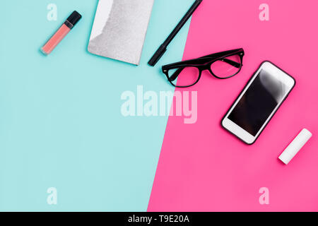Home office desk with calligraphic pen, glasses, Notepad, smartphone and lipstick on a colorful background with copy space Stock Photo
