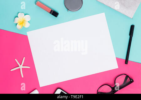 White A4 blank frame on a colorful pink and blue background with womens accessories, top view. Lipstick, mirror, yellow flower, glasses, pen, shells l Stock Photo