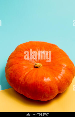 Halloween with the orange of ripe pumpkin on a yellow and blue colored background with copy space. Minimal, autumn, holiday concept Stock Photo