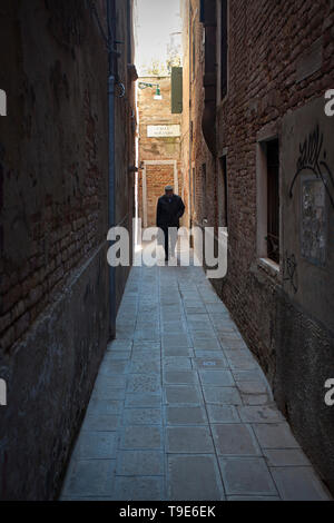 Man walking alone in alley Stock Photo