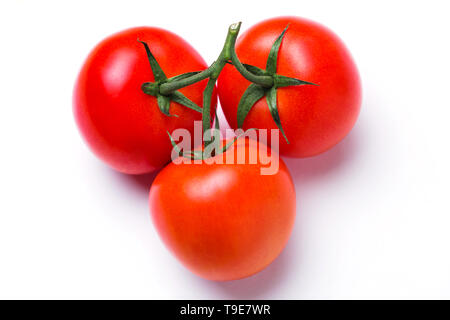Closeup of three red fresh tomatoes in a pile in a green stalk on white isolated background, top view. Healthy diet, vegetarian food Stock Photo