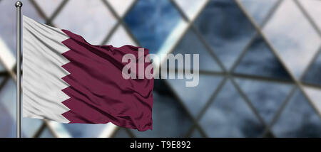 Qatar flag waving in the wind against blurred modern building. Business concept. National cooperation theme. Stock Photo