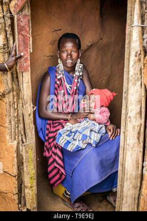 MASAI VILLAGE, KENYA - OCTOBER 11, 2018: Unindentified african woman with a baby wearing traditional clothes in Masai tribe, Kenya Stock Photo