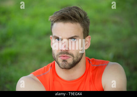 Taking minute break. Runner relaxing in shadow. Man with bristle strict face, grass background. Man unshaven looks handsome and cool. Guy bearded and  Stock Photo