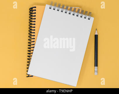 Notebook and pencil on an orange yellow background. Top view with copy space. Stock Photo