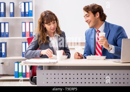 Two colleagues having lunch break at workplace Stock Photo