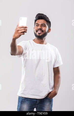 Young handsome Indian man taking selfie with mobile phone Stock Photo