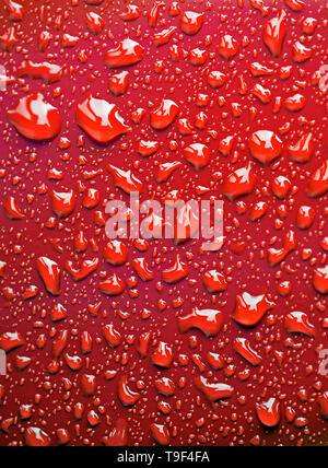 Abstract of light reflections in water droplets on a bright red metallic background. Stock Photo