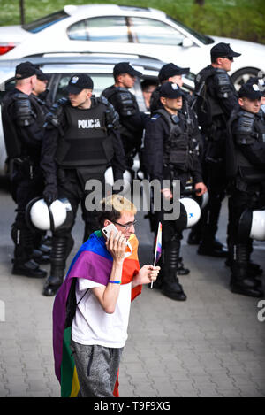 Krakow, Poland. 18th May, 2019. A man seen wearing a Rainbow flag as he walks by police officers during the 15th Equality Parade rally in support of the LGBT community.During the pro LGBT parade route, several protests against LGBT rights and promoting pro family values were organized by polish far right and conservative associations. Credit: Omar Marques/SOPA Images/ZUMA Wire/Alamy Live News Stock Photo