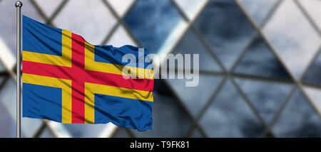 Aland Islands flag waving in the wind against blurred modern building. Business concept. National cooperation theme. Stock Photo