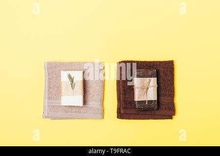 Two hygiene sets of organic soap bars and towels on yellow background, flat lay. Stock Photo