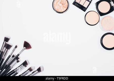 Makeup powders for face skin cover and set brushes on white background, flat lay. Stock Photo