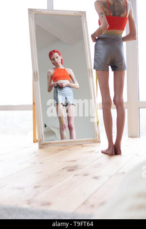 Skinny anorexic woman with long legs sitting near the window Stock