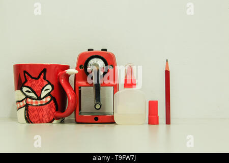 Red pencil sharpener machine with cup and glue on white background Stock Photo