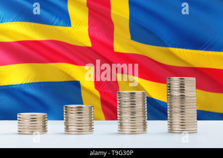 Aland Islands flag waving in the background with rows of coins for finance and business concept. Saving money. Stock Photo