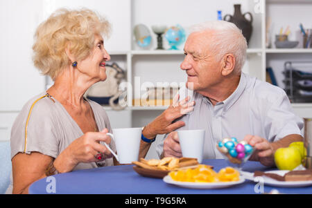 Portrait of happy mature couple having good time drinking tea in kitchen Stock Photo