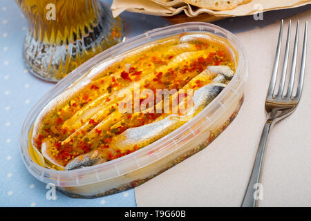 Preserved sardines marinated with spices in plastic container Stock Photo