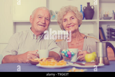 Portrait of happy mature couple having good time drinking tea in kitchen Stock Photo